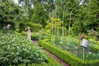 A stone plinth marks the centre of a Buxus - Box framed vegetable garden with Tomatoes, Potatoes, Onions and Beans
