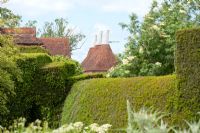 Traditional houses in Kent obscured by hedge.
