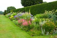 Herbaceous Border in early July backed by a Taxus - Yew hedge. Between the beds are handsome Yew finials designed by Rowland Egerton-Warburton and planted in 1856 - Arley Hall, Cheshire, early July