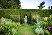 Pathway through a clipped Taxus - Yew hedge flanked by Yew finials. Designed by Rowland Egerton-Warburton and planted in 1856 - Arley Hall, Cheshire