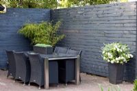 Contemporary dining area with black stained screen and pots of Bamboo and Petunias - Lipkje Schat Garden