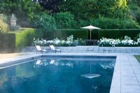 Swimming pool with loungers and white border 
