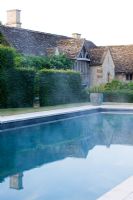 Swimming pool with country house reflected in it
