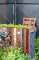 Storage made from recycled wood with 'living roof' next to steel-framed metal structure in the Stockton Drilling Winds of Change Garden, Gold Medal Winner - RHS Chelsea Flower Show 2011 
