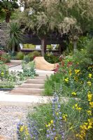 Seating area with curved timber bench and salt tolerant planting including Crambe maritima - Sea Kale, Armeria - Thrift, and Centranthus ruber - The Cancer Research UK Garden, Silver Gilt Medal Winner, RHS Chelsea Flower Show 2011 