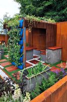 Living roof on rusting steel wall summer house with reclaimed steel tanks used as seats. Extensive vertical planting in wally pockets on back wall. RHS Tatton Park Flower Show 2011
