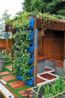 Living roof on rusting steel wall summer house with reclaimed steel tanks used as seats. Extensive vertical planting in wally pockets on back wall. RHS Tatton Park Flower Show 2011
