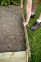 step by step, making a raised bed - using sticks to mark out trench and sizing up plank