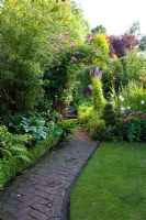 Old brick path with herringbone patten leads up cottage garden - Merlin House, Wiltshire, UK 