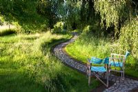 Summer garden, cobble and brick paths wend their way through informal borders - The Corner House, Wiltshire. 