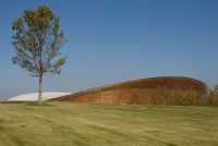 Olympic Park, London. The Velodrome designed by Hopkins Architects seen from man made land form with lone tree. 