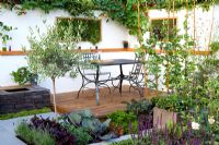 Eating area on timber decking surrounded by edible garden, vertical wall planters with scented herbs