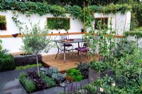 Small contemporary garden with edibles in containers and vertical wall planting of scented herbs. 