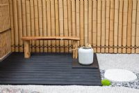 Seating area, bamboo fence and granite stones and gravel path in a Japanese themed garden  - 'Less and More' garden - RHS Hampton Court Flower Show 2011
 