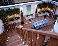 Roof garden with decking, glass water feature, clipped box, standard Photinias, silver table and chairs