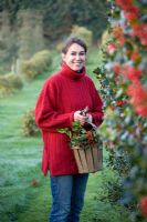 Woman in red jumper carrying wooden basket of mixed Hollies
