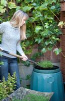 Woman filling compost bin with lawn cuttings