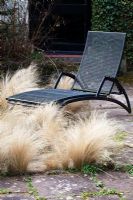 Metal recliner and Stipa tenuissima 'Pony Tails' on terrace