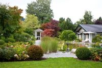 German garden with pavilion, garden pond, grasses and Box spheres. Plants include - Acer negundo 'Variegatum', Acer palmatum, Acer saccharinum, Betula pendula, Buxus, Hydrangea, Miscanthus sinensis, Pinus, Rhododendron, Taxus baccata and Wisteria