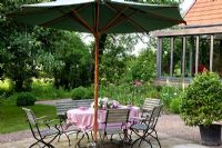 Relaxing area with wood and metal garden furniture and parasol. Planting includes - Allium aflatunense 'Purple Sensation', Buxus, Camellia japonica and Digitalis purpurea 'Alba' - Jens Tippel