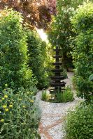 Concrete and cobblestone pebble path and water fountain. Planting includes Phlomis Citrus and Aesculus - Madrid, Spain 