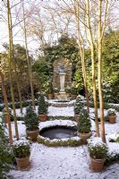 Formal garden with circular pond and evergreens in terracotta pots - The Old School House, Great Bentley, Essex in January
