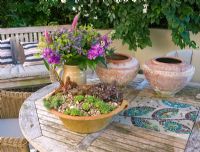 Containers on wooden patio table with mosaic insets