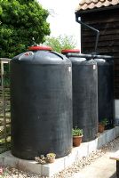 Bulk rainwater collection in ex-industrial orange juice vessels, with connecting overflow pipes - Open Gardens Day 2011, Newbourne, Suffolk