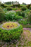 The Flower Garden features strong blocks of box and yew that frame cottage garden plants and flowers, stone container planted with saxifrages and clothed in clipped ivy - Herterton House, Hartington, Northumberland, UK