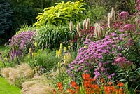 Mixed border. From front to back - Crocosmia x crocosmiiflora 'Constance', Monarda 'Violet Queen', Verbena bonariensis, Stipa tenuissima, Geranium x 'Rozanne', Kniphofia 'Percy's Pride', Cortaderia selloana 'Patagonia', Liatris spicata 'Kobold', Miscanthus sinensis 'Superstripe', Monarda 'Raspberry Wine', Catalpa bignonioides 'Aurea'