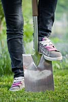 Teenage girl wearing sneakers with garden spade in the garden