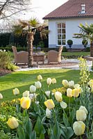 Seating area with planting of Tulipa 'Maja', Tulipa 'Verona', Tulipa 'Francoise', Tulipa 'Ivory Floradale' and Fritillaria persica 'Ivory Bells'
