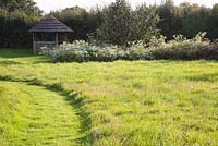 Wild garden with mown grass pathway leading to gazebo