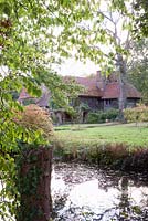 View of 16th Century house across the pond, forming part of Gertrude Jekyll's Water Garden - Vann, Surrey