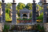 The allegorical River Arun emerges from a rocky grotto framed by a scallop shell pediment and muscular caryatids. It flows along a rill pool flanked by turned oak urns spouting water through gilded lions' heads, with golden agaves in their tops. and spills over a scallop edged cascade into a pool below. The Collector Earl's Garden designed by Julian and Isabel Bannerman.