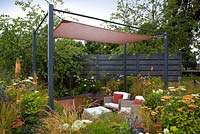 Modern wicker furniture on patio surrounded by Eryngium, Achilleas and grasses - 'The Landform Garden' - Gold medal winner and Best Summer Garden - RHS Hampton Court Flower Show 2012 
