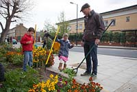 Man and children tidying the Edible Bus Stop