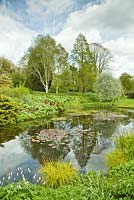 View of pond area surrounded by mature trees and shrubs and water loving plants - Dorothy Clive Garden NGS in late spring, Staffordshire