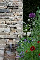 Contemporary stone waterfall set into stone pier with naturalistic planting 
