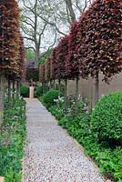 Cobblestone path leading to Bronze Bird sculpture by the late Breon O'Casey with pleached Fagus sylvatica 'Atropunicea' - The Laurent-Perrier Garden

