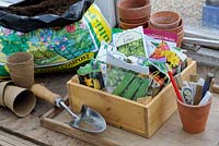 Box of seed packets on the greenhouse potting bench with flowerpots, April
