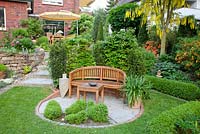 Circular patio with wooden bench and box topiary