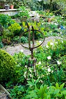 Rusty metal sundial in spring border with Tulipa 'Vanilla Ice'
