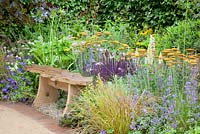 Wooden bench backed by planting of Salvia nemorosa, Achillea 'Terracotta', Lupinus, Geranium and Anemanthele lessoniana