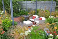 Seating area surrounded by Achillea 'Terracotta', Anemanthele lessoniana, Allium caeruleum 'Azureum', Euphorbia walichii, Eryngium 'Saphire Blue' and Trifolium ochroleucum
