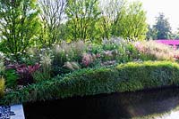 Extensive planting along bridge with Gleditsia, grasses, perennials and the side lined with ferns and grasses. 'Bridge Over Troubled Water garden', Hampton Court Palace Flower show 2012