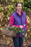 Woman holding basket of cut foliage from the garden in winter 