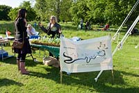 Kathryn Lwin from River of Flowers, a social enterprise which encourages wild flowers in the city environment, talking to a lady in front of her stall at the Camden, now London Green Fair, Regent's Park, Central London