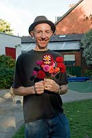 Man in pork pie type hat holding a bunch of mixed Dahlias 