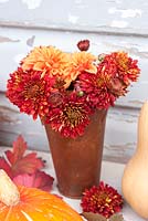 Chrysanthemums and dahlia in rusty jug with squashes